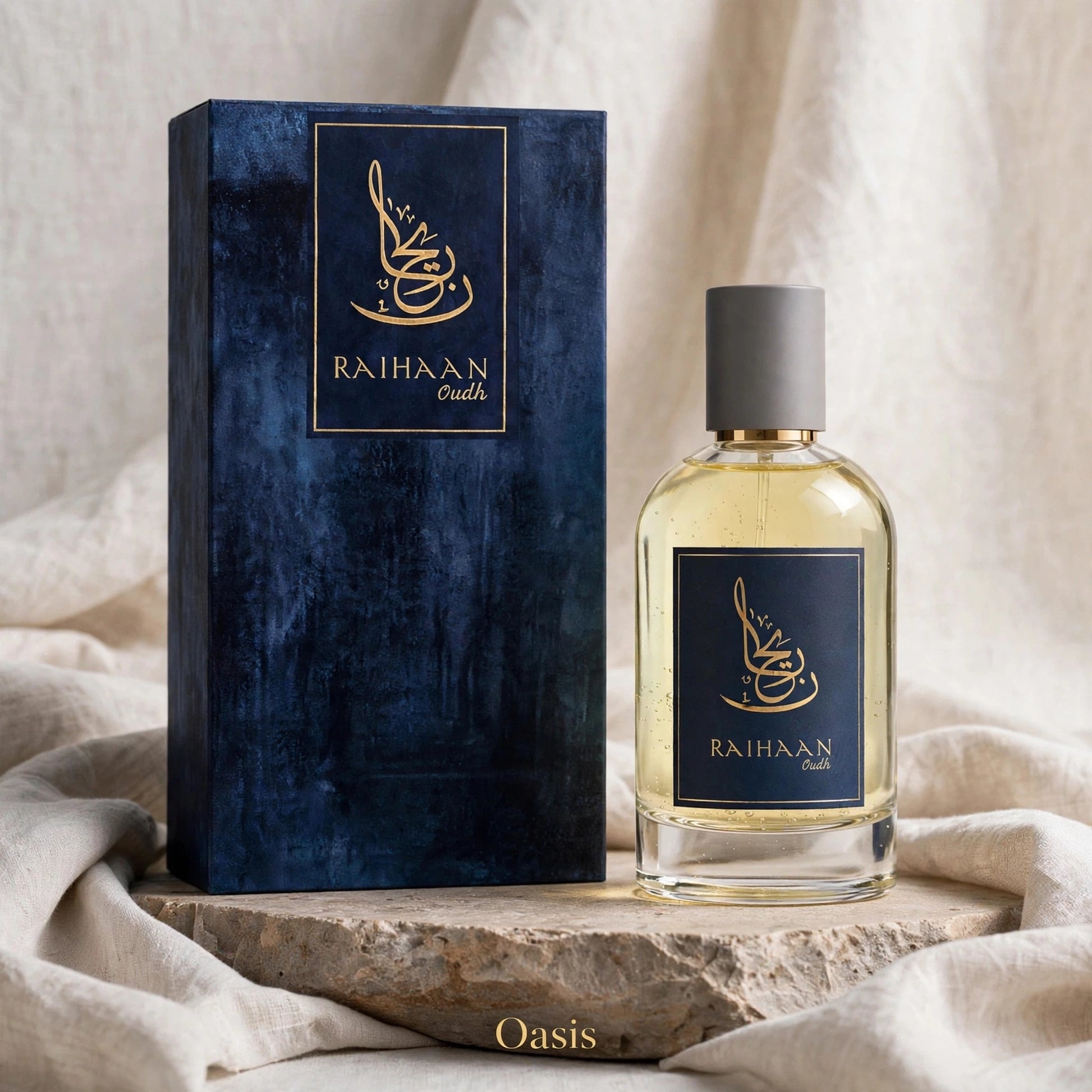 A bottle of Raihaan Oasis perfume next to its dark blue textured box, styled on a stone slab with draped beige fabric in the background.